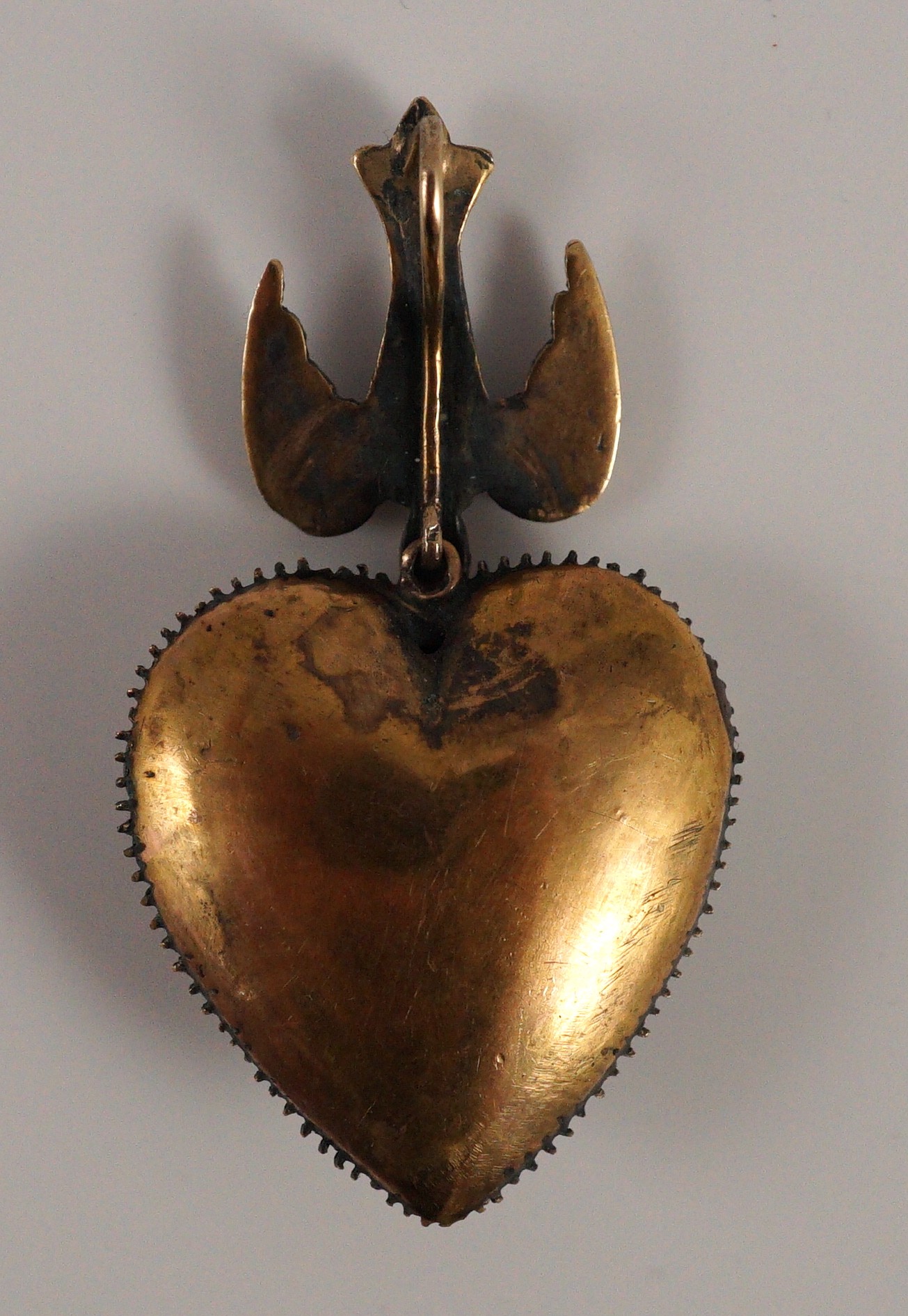 A Victorian style gold and graduated rose cut diamond set heart shaped pendant, with diamond and spinel? set bale modelled as a swallow